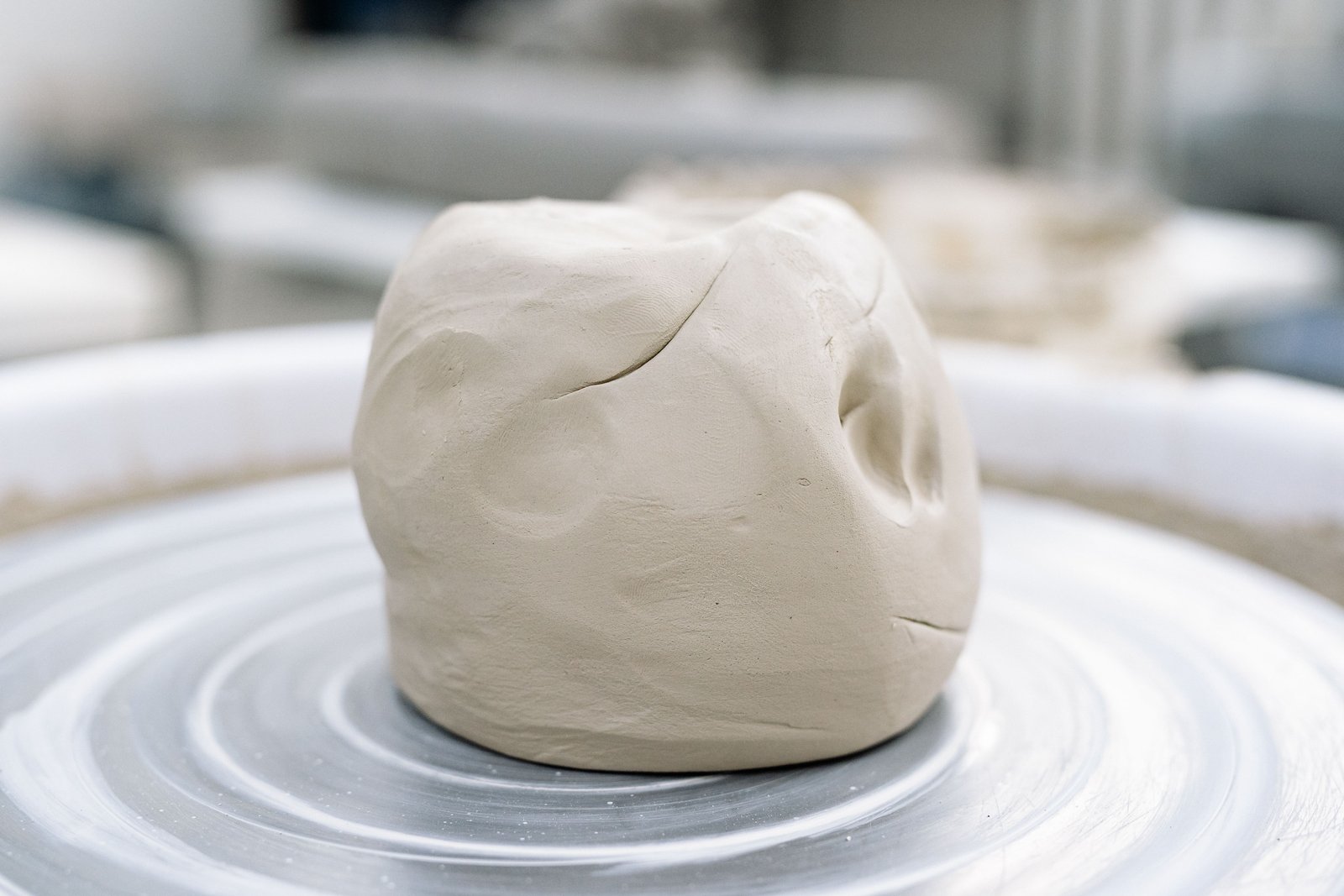 Beginner pottery student centering clay on the wheel during a class