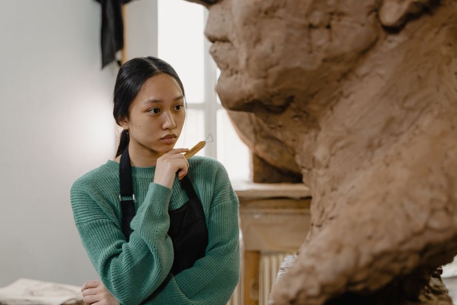 Sculptor working on a large clay sculpture, where good clay sculpting equipment becomes essential