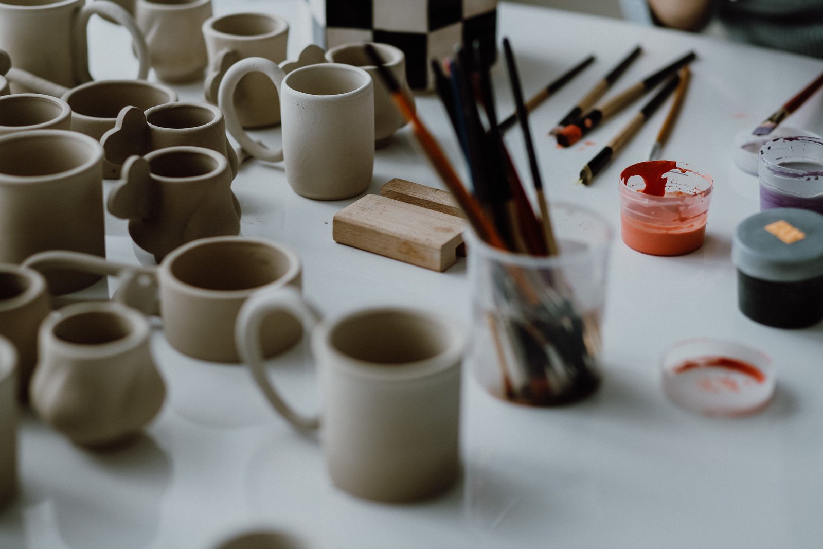 Pottery tools and unpainted ceramic mugs ready for decorating