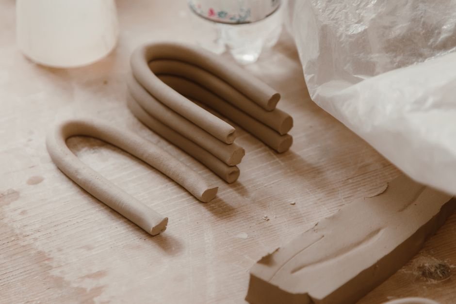 Raw clay strips on a pottery workbench, showing what ceramic is made of before firing