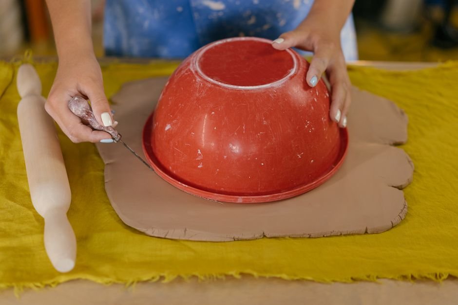Hands shaping clay with a rolling pin, the basic skills a pottery starter kit introduces