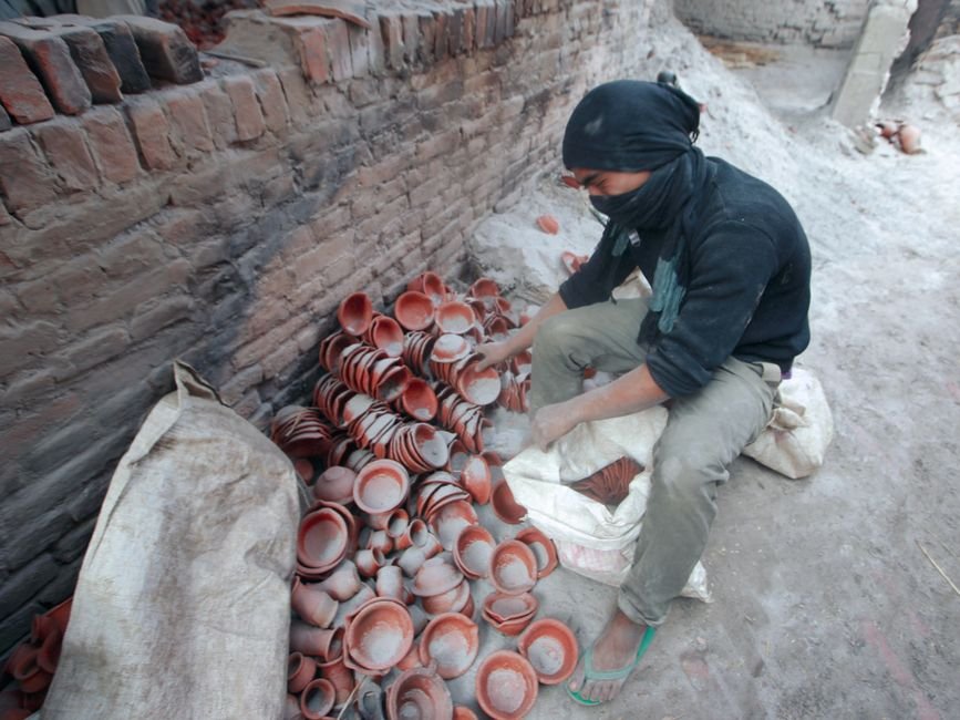 Man arranging clay pots in a pottery workshop, the kind of loading routine behind top loading vs front loading kilns