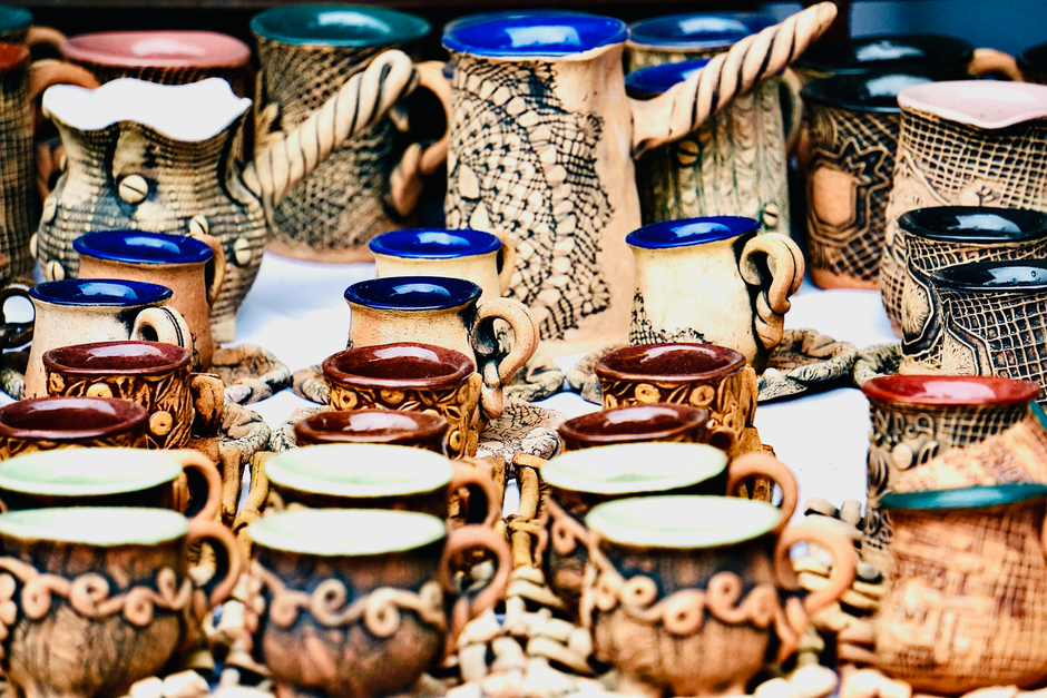 Handcrafted ceramic mugs on display at a craft market stall, a common first step for a pottery business