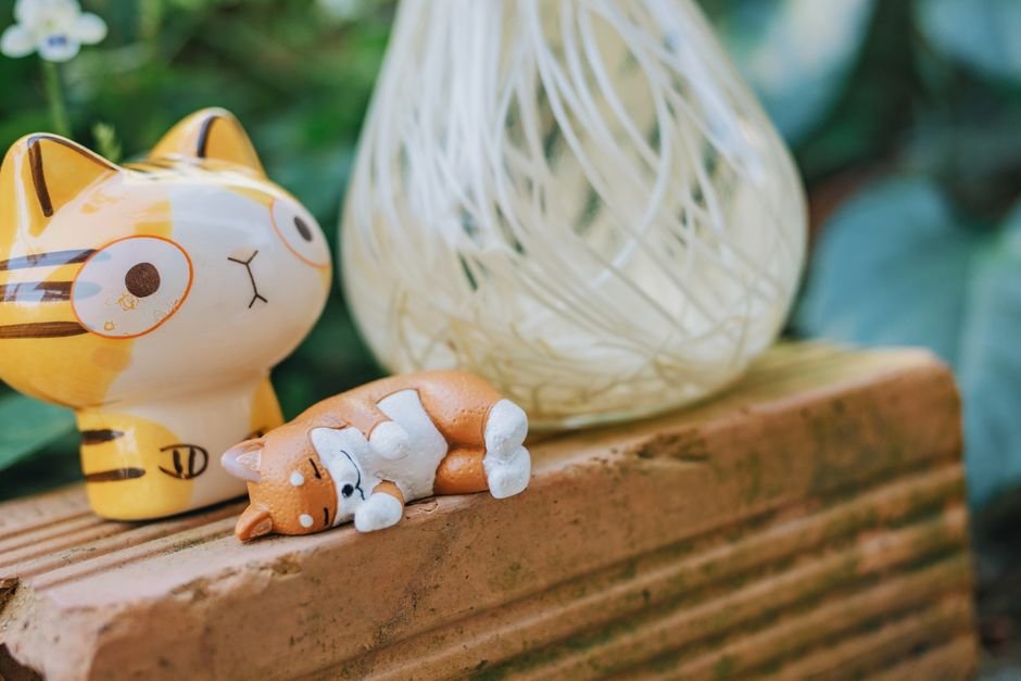 Small ceramic cat figurines on a brick surface, a simple answer to what is a figurine
