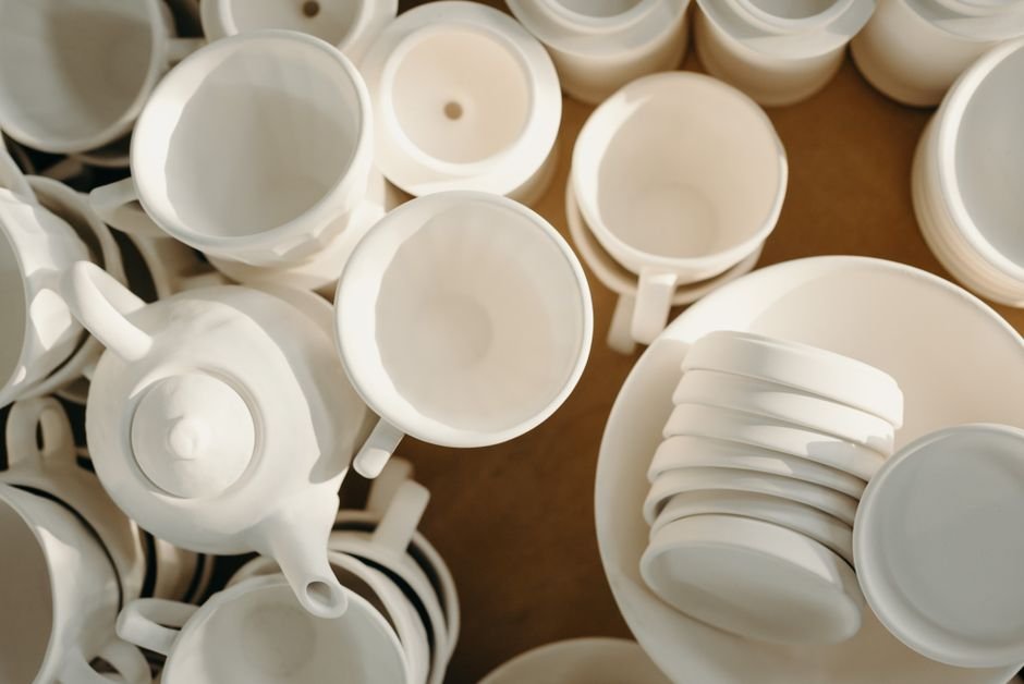 White ceramic cups, teapots, and plates from above, raising the porcelain glass question