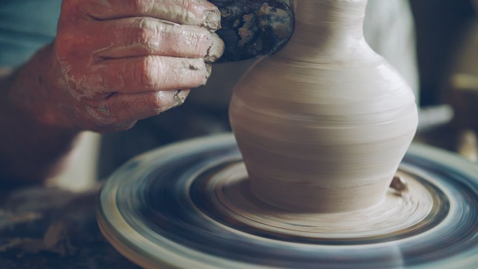 Potter shaping a vase on a spinning wheel, the kind of form that may need a pottery trimming chuck