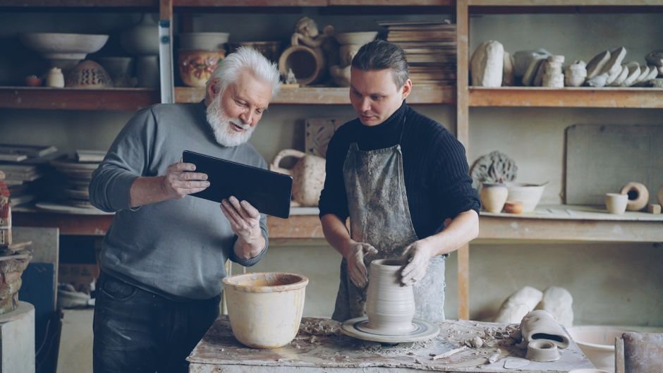 Instructor guiding a student in a pottery class, one of the most common ceramic jobs