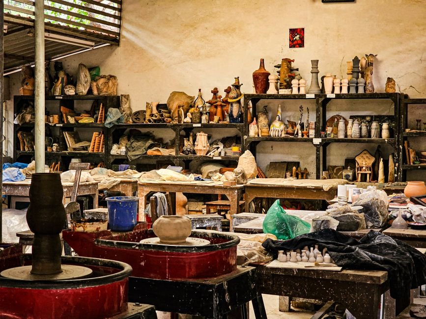 Pottery and tools spread through a busy workshop, showing a working ceramic studio layout in action