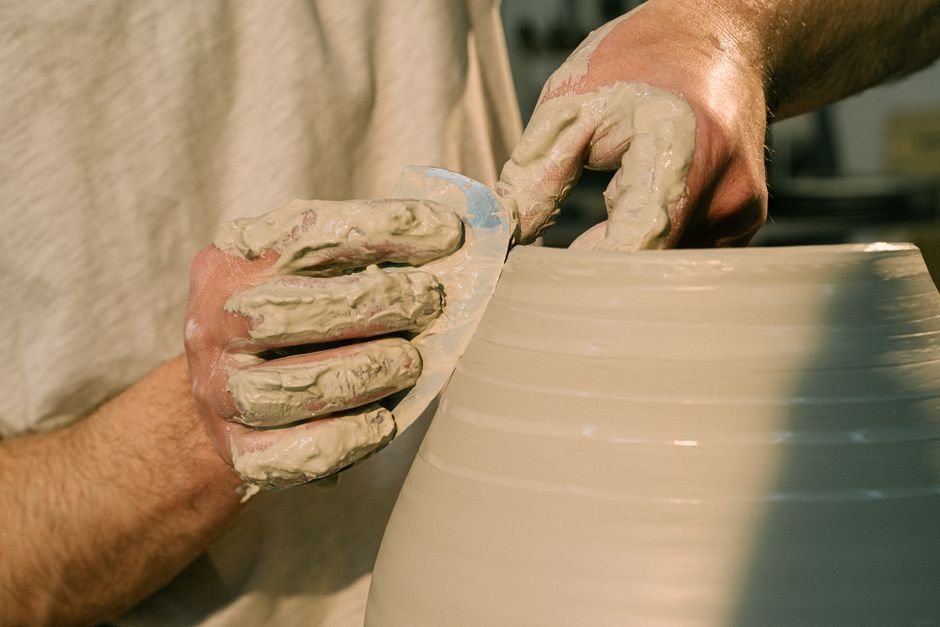 Artisan shaping a clay pot by hand, before trimming with a pottery trimming chuck