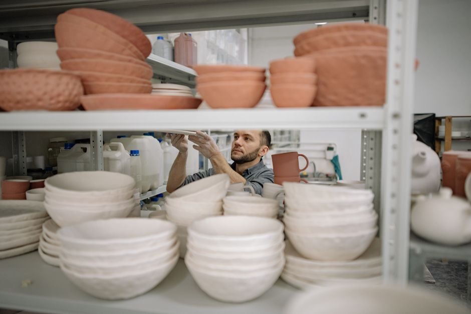 Potter organising fired ceramic bowls in a workshop, after a cone 6 vs cone 10 firing