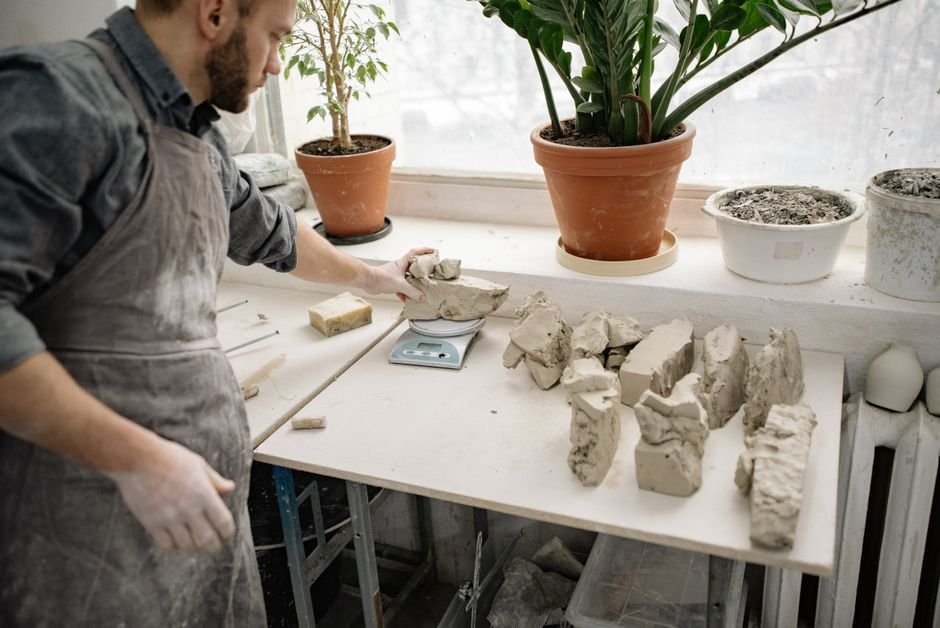 Potter weighing pieces of clay on a scale, useful when working out how much to order and where to buy pottery clay