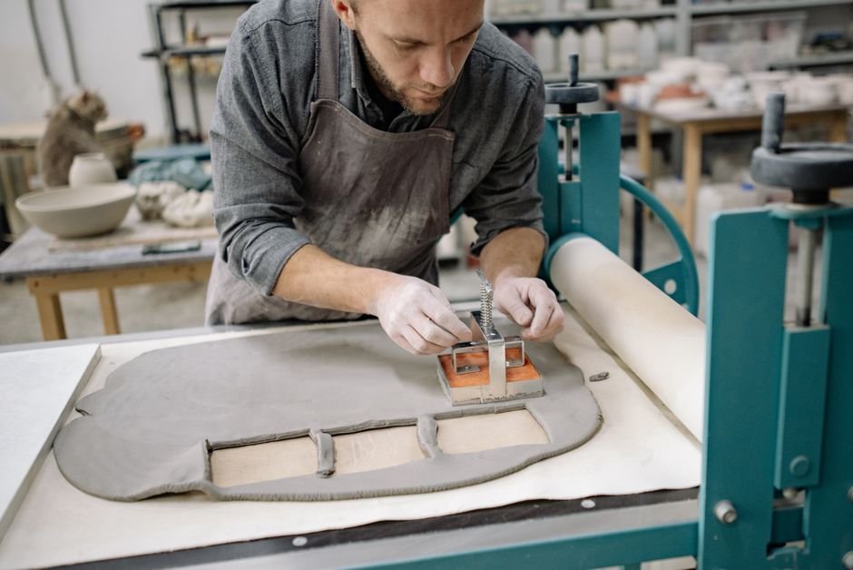 Artisan cutting clay against a stencil in a workshop, the kind of slab work a mud knife suits