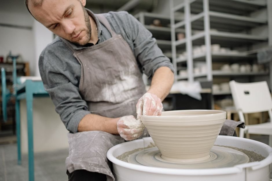 Potter shaping a bowl on the wheel before trimming, when a pottery trimming tool kit comes into play