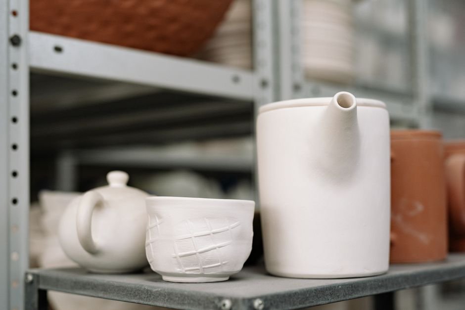 Unfired white clay pieces on an industrial shelf, an example of greenware ceramics waiting to dry