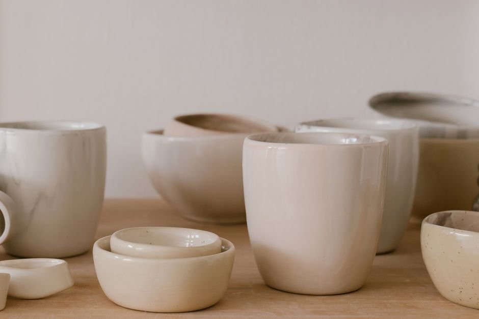 Handcrafted ceramic bowls and cups on a wooden table, a clear example of handmade vs mass produced ceramics