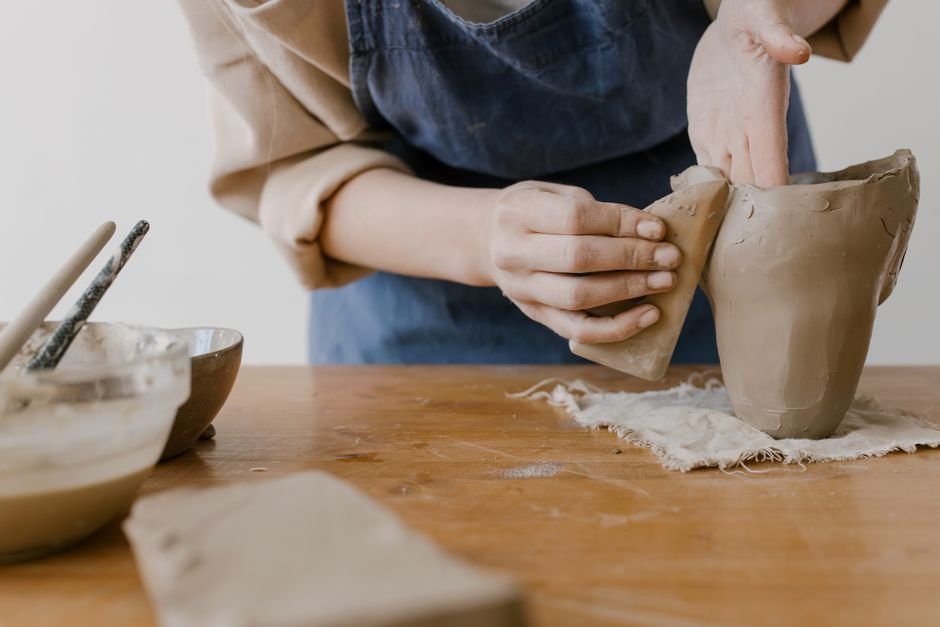 Close up of hands pressing clay on a worktable, the hands on part of using a wedge tool