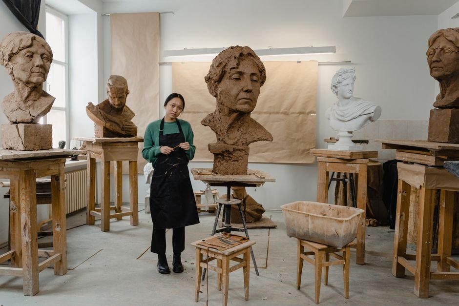 Sculptor working on clay busts in a studio, showing model making that can involve tooling clay