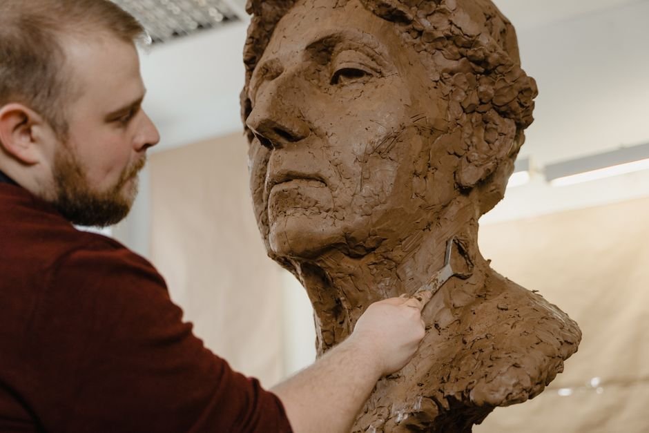 Sculptor refining a clay bust with a loop tool, the kind of modelling work where tooling clay is used