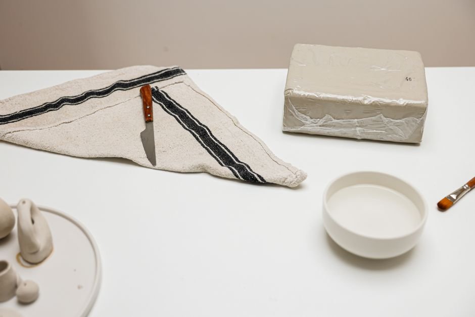 Ceramic artist workspace with a block of clay and tools, the kind of setup beginners have when deciding where to buy pottery clay