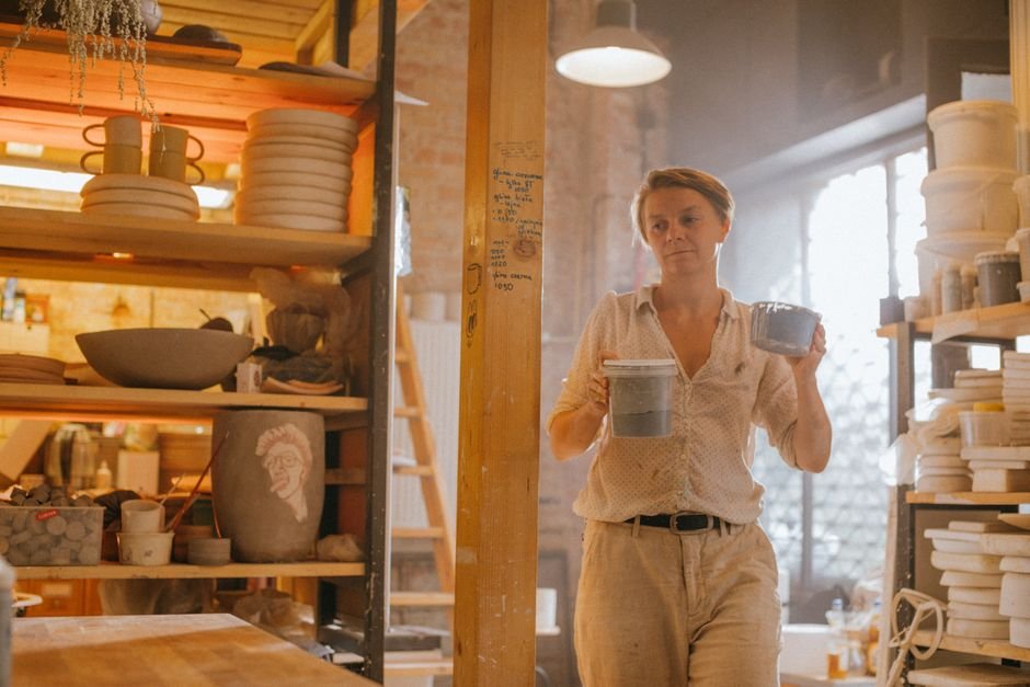 Artist holding finished ceramic bowls, the end of the pottery studio journey from wet clay to finished piece